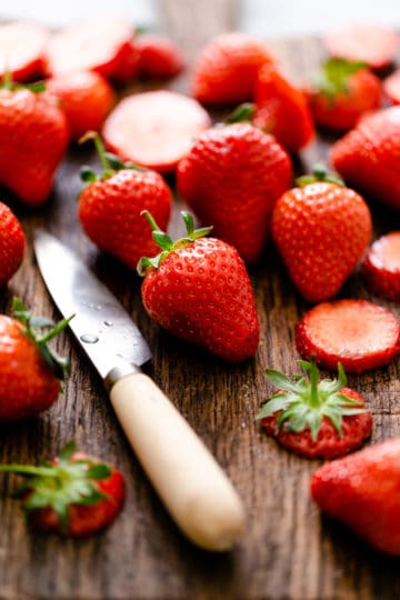a close up of fresh strawberries on a wooden chopping board