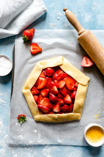 top view of unbaked strawberry galette on a blue background