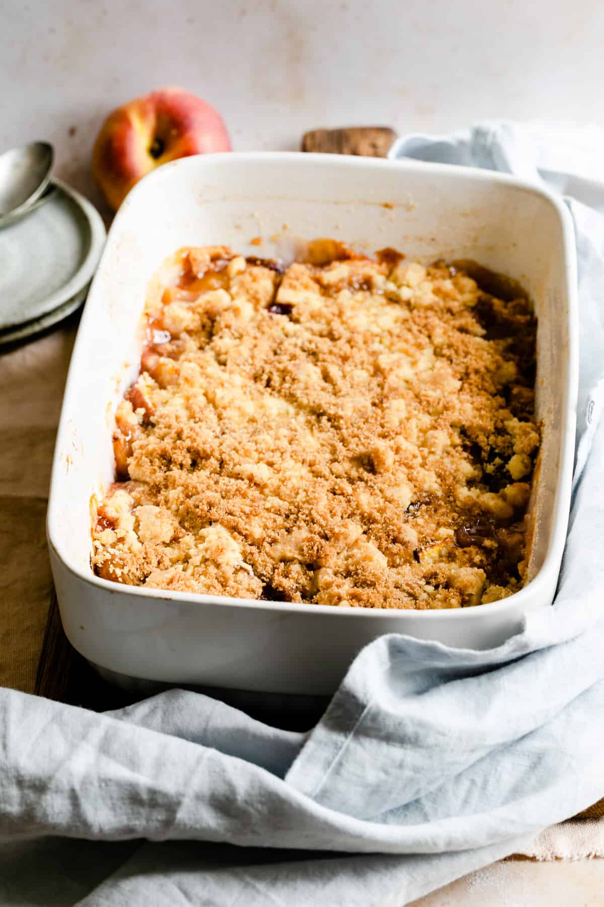 baked peach cobbler in a white baking dish