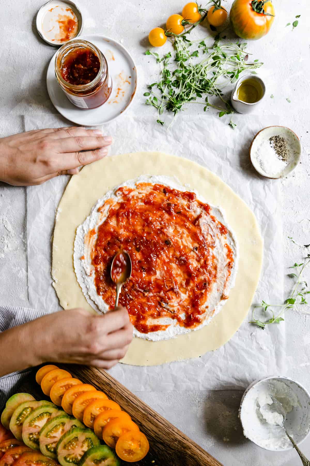 overhead shot of a person spreading some tomato jam on galette crust