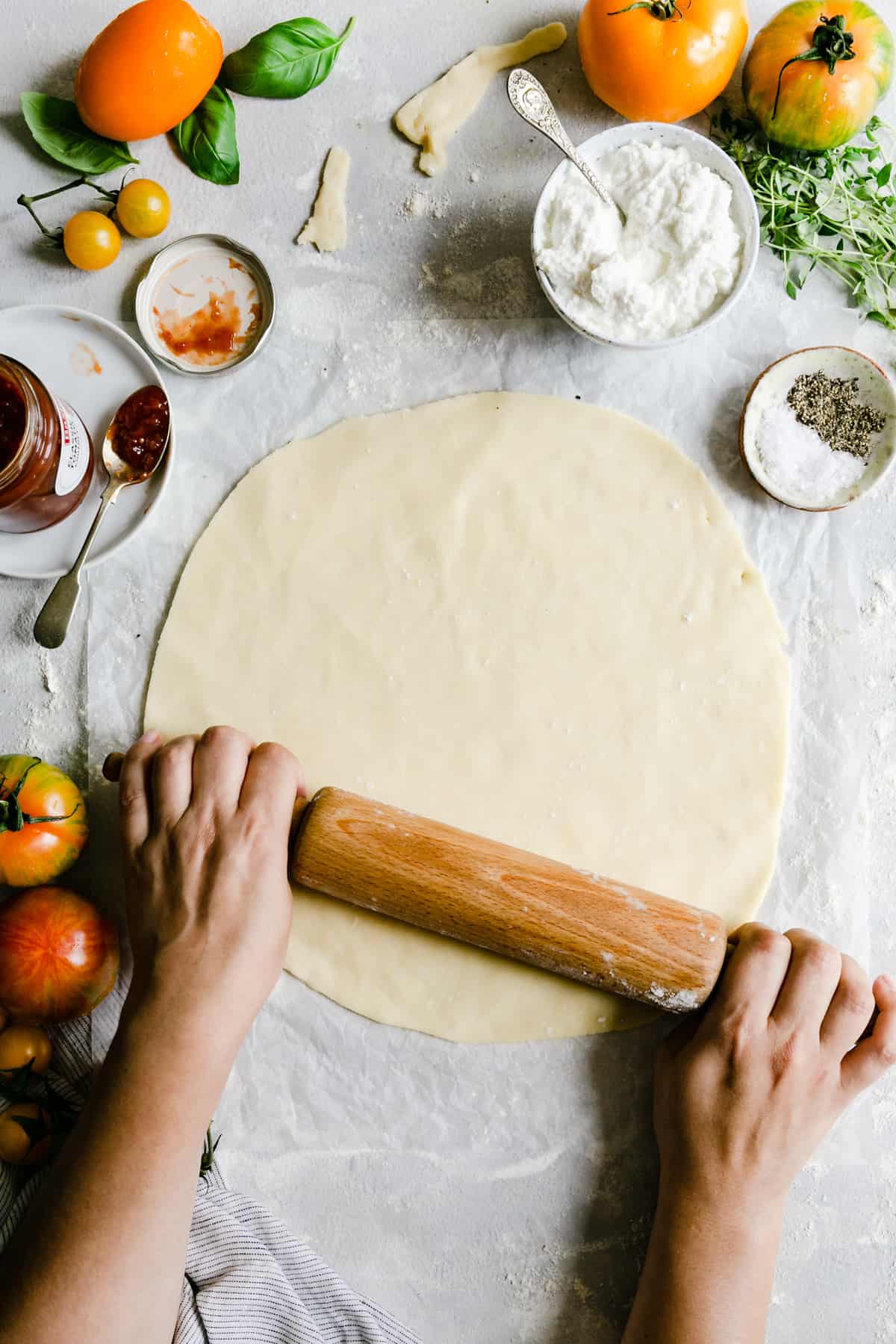 overhead shot of a person rolling pastry into a large circle with rolling pin