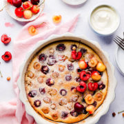 Overhead view of baked clafoutis in a baking dish topped with fresh cherries