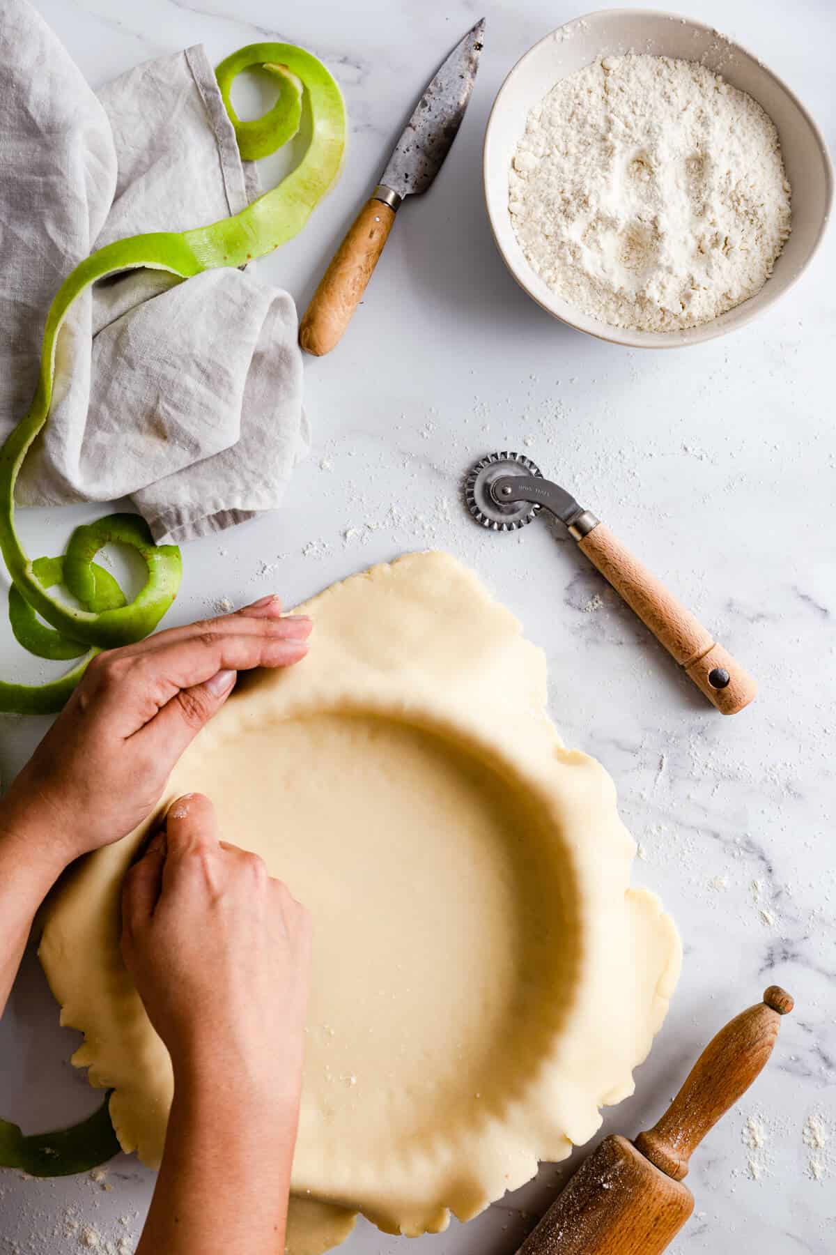 overhead shot of a person pressing rolled pastry into baking tin