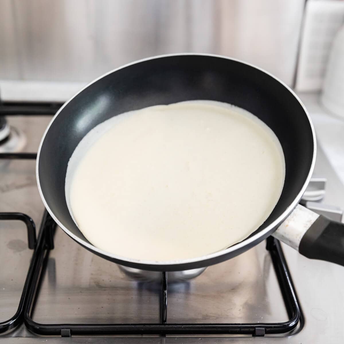 side angle view at crepe batter poured into frying pan