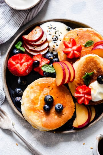 overhead shot of a plate with pancakes and selection of fruits.