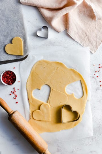 overhead shot of rolled out cookie dough with hearts cut out of it