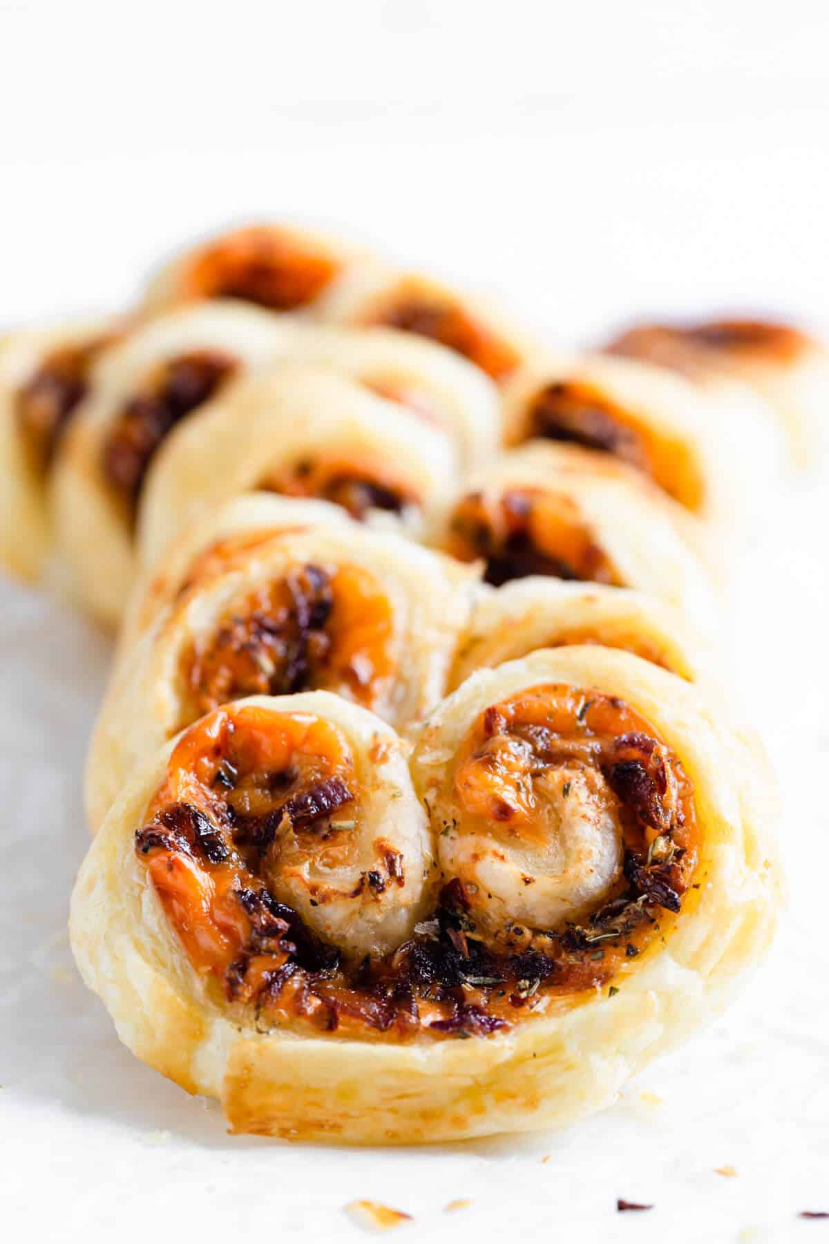 super close up of cream cheese and caramelised onion palmiers on white surface