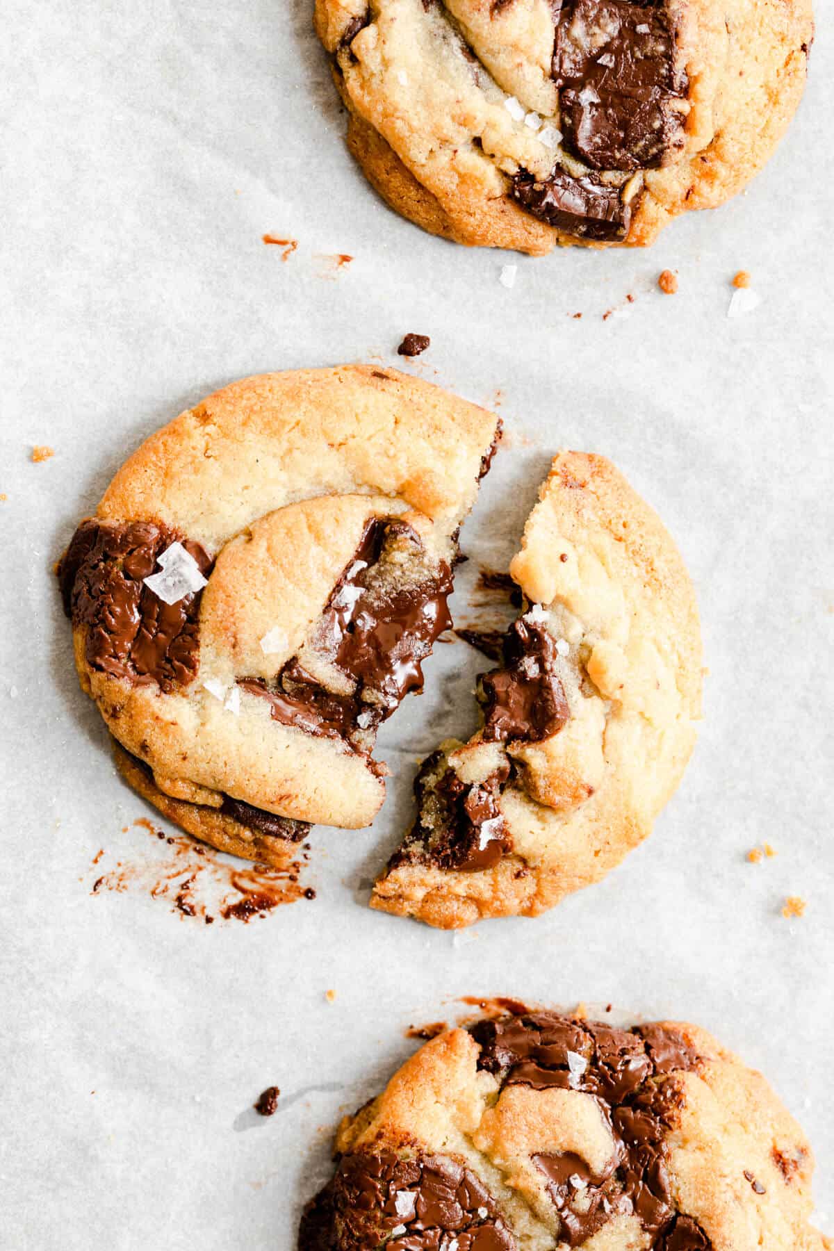 close up of a chocolate chip cookie broken in half revealing melted chocolate inside