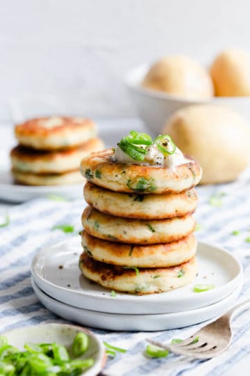 a side shot of stack of potato patties on a white plate
