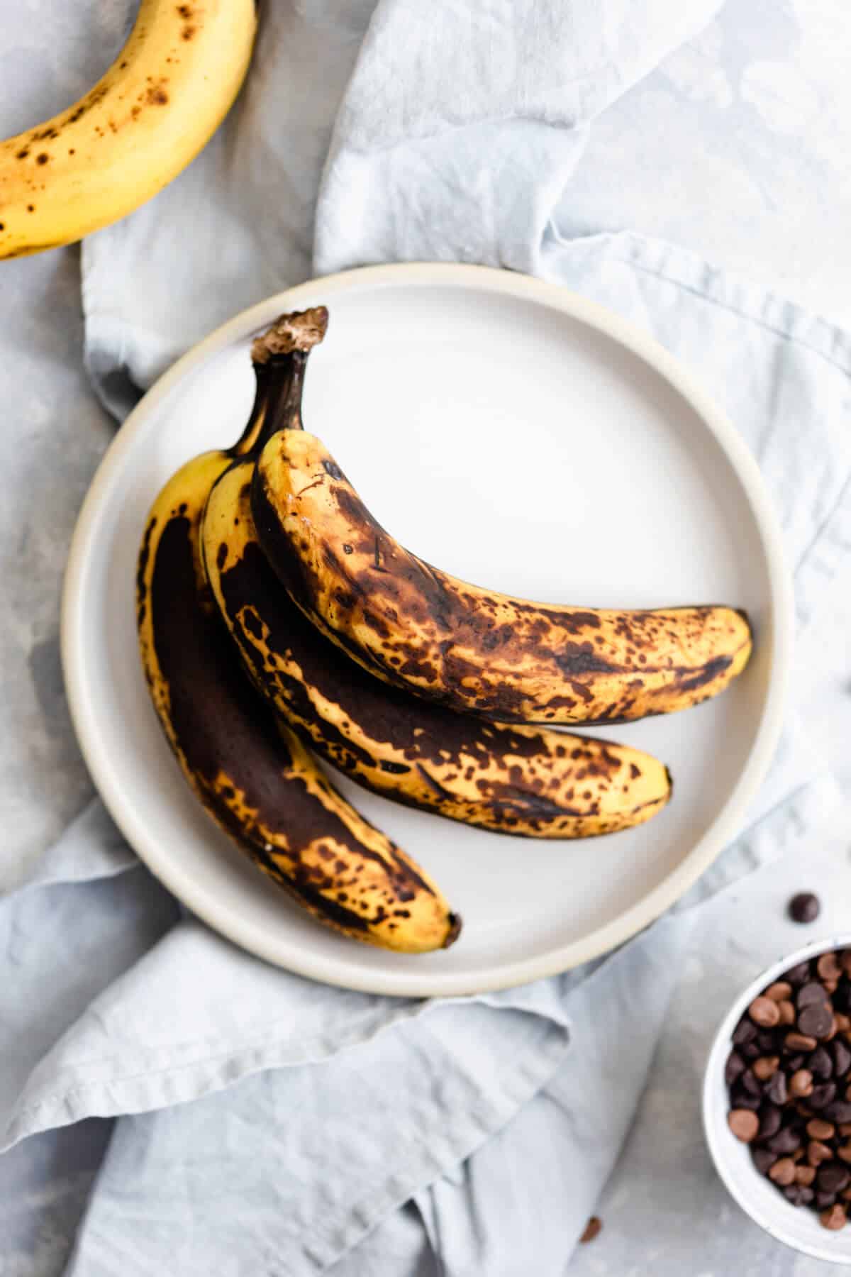 top view of 3 ripe bananas on a white plate