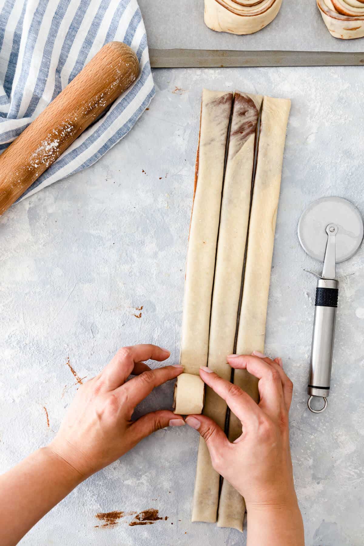 top view of a person rolling strips of dough