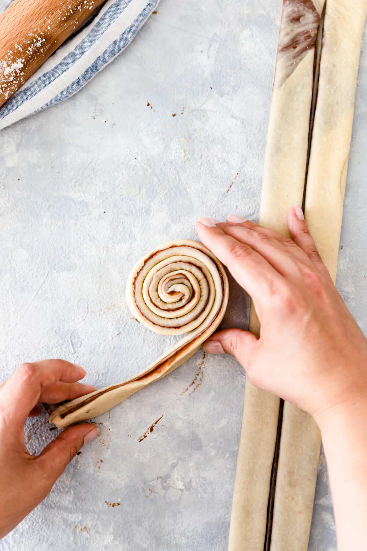 overhead shot of strip of dough being rolled into swirl
