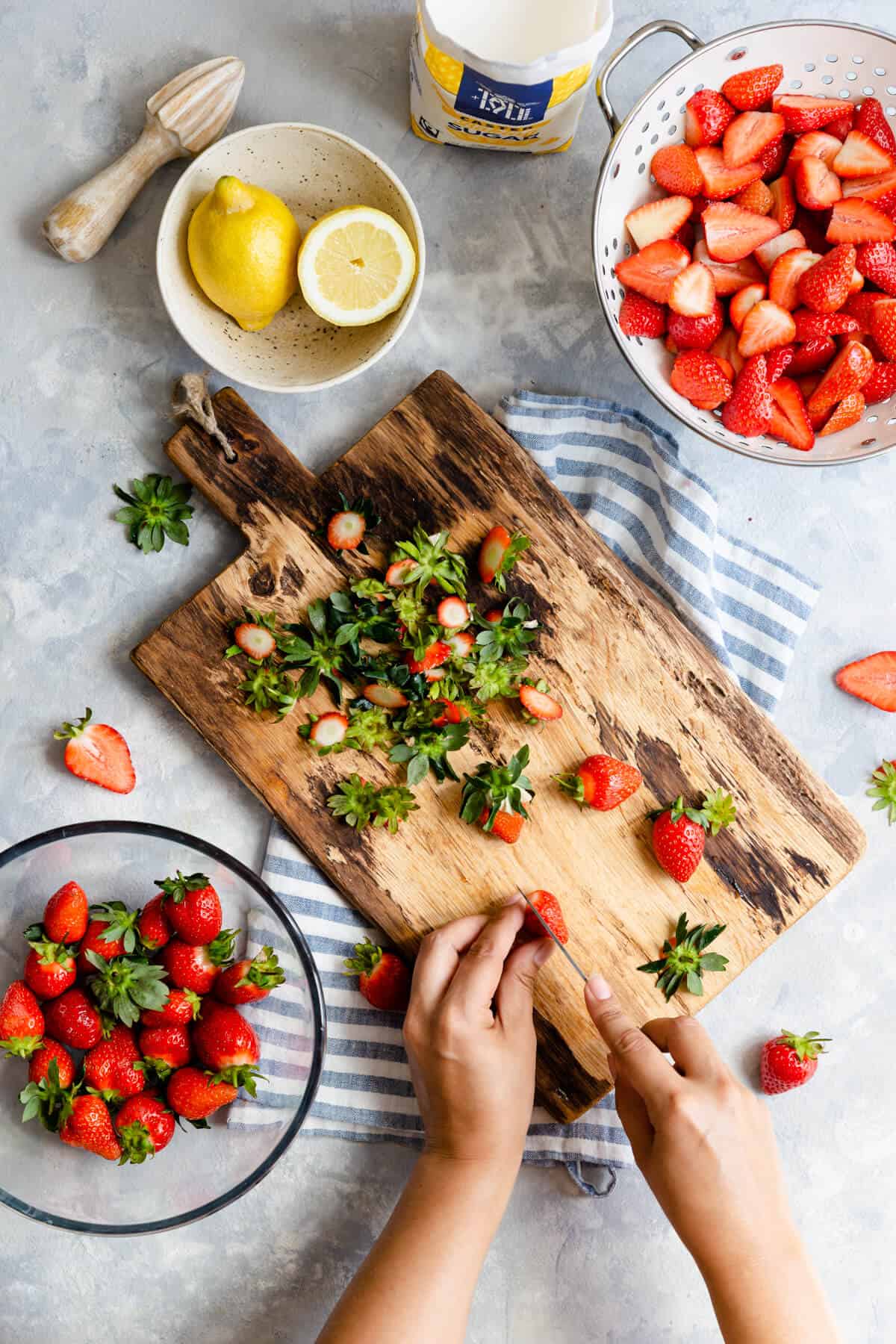 overhead shot of a person slicing strawberries on a chopping board