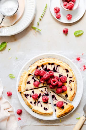 overhead shot of sliced raspberry cheesecake topped with fresh raspberries