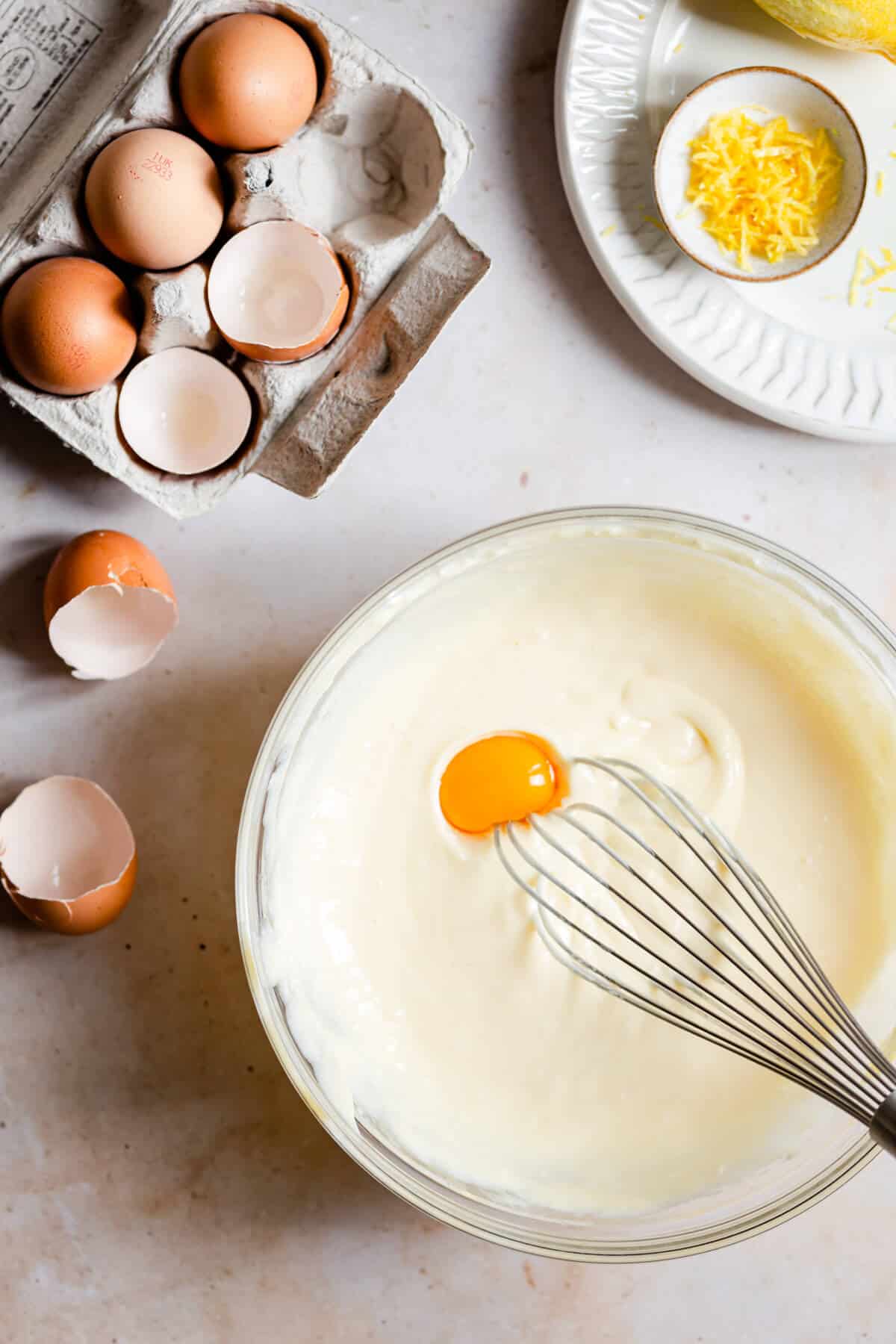 overhead shot of a bowl with cheesecake batter and egg yolk inside