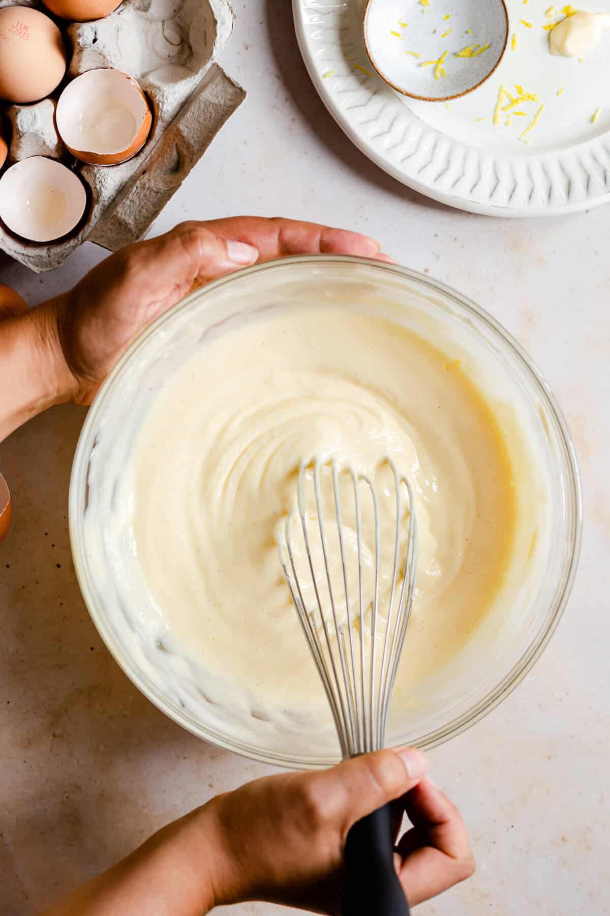 top view of a person whisking cheesecake batter in a large bowl