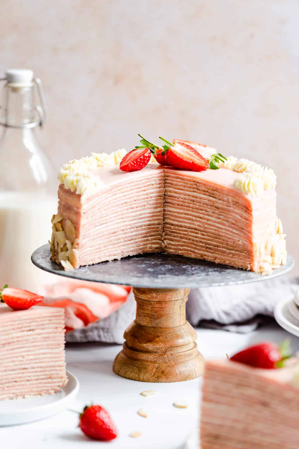 straight ahead shot of a strawberry crepe cake with couple of slices cut out revealing its inside