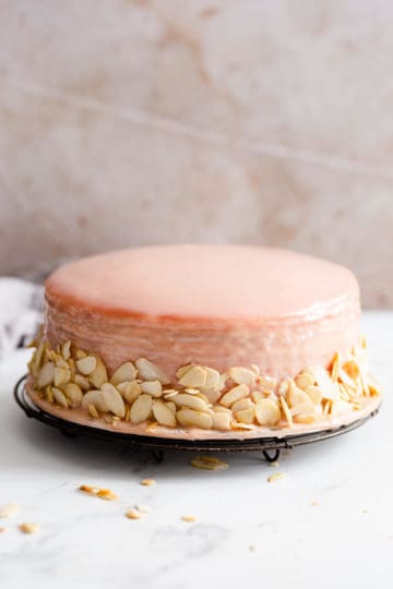 straight ahead angle showing crepe cake covered in strawberry ganache and flaked almonds on sides
