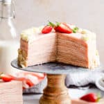 straight ahead shot of a strawberry crepe cake with couple of slices cut out revealing its inside