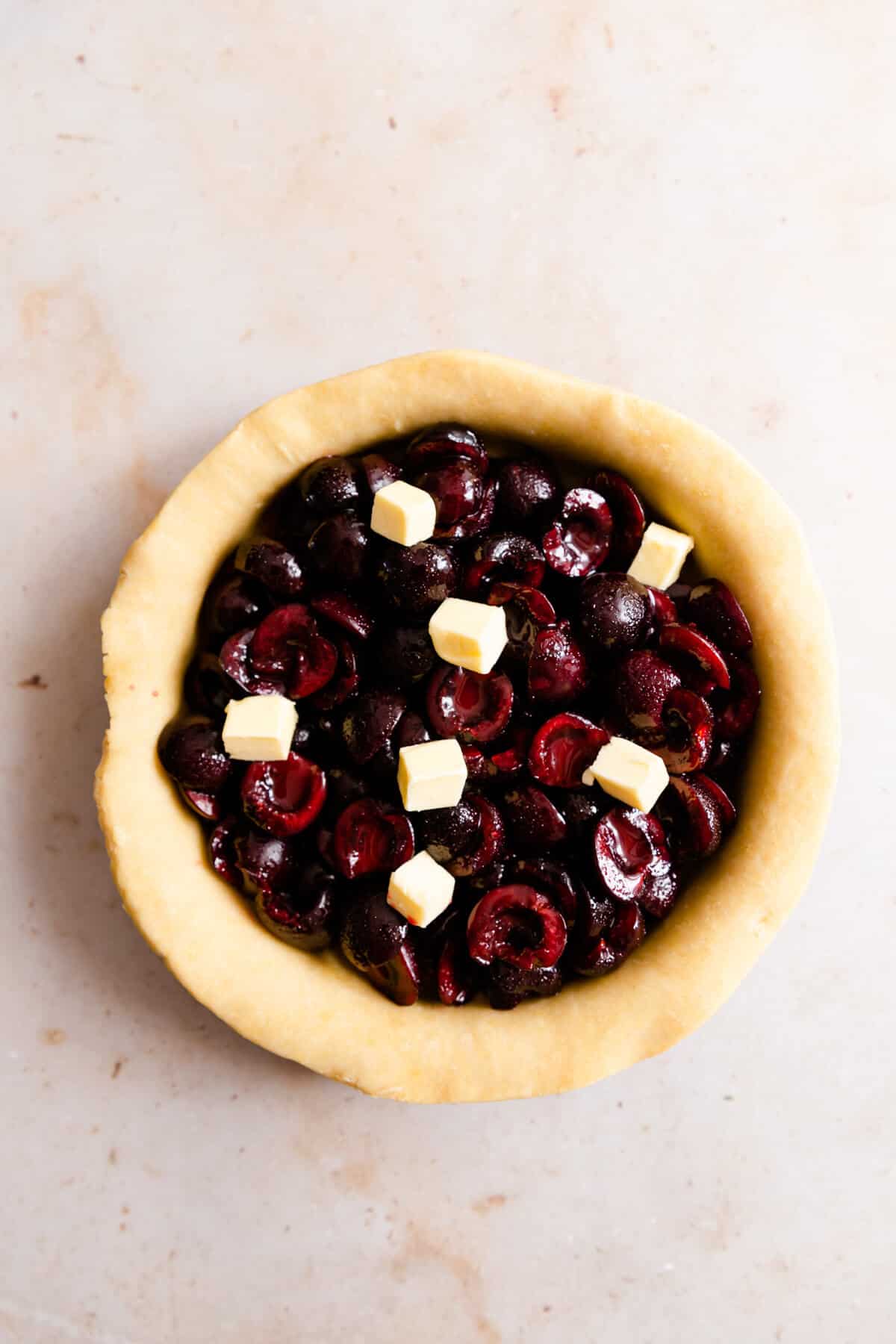 overhead shot showing cherry filling in a pie dish with small cubes of butter on top