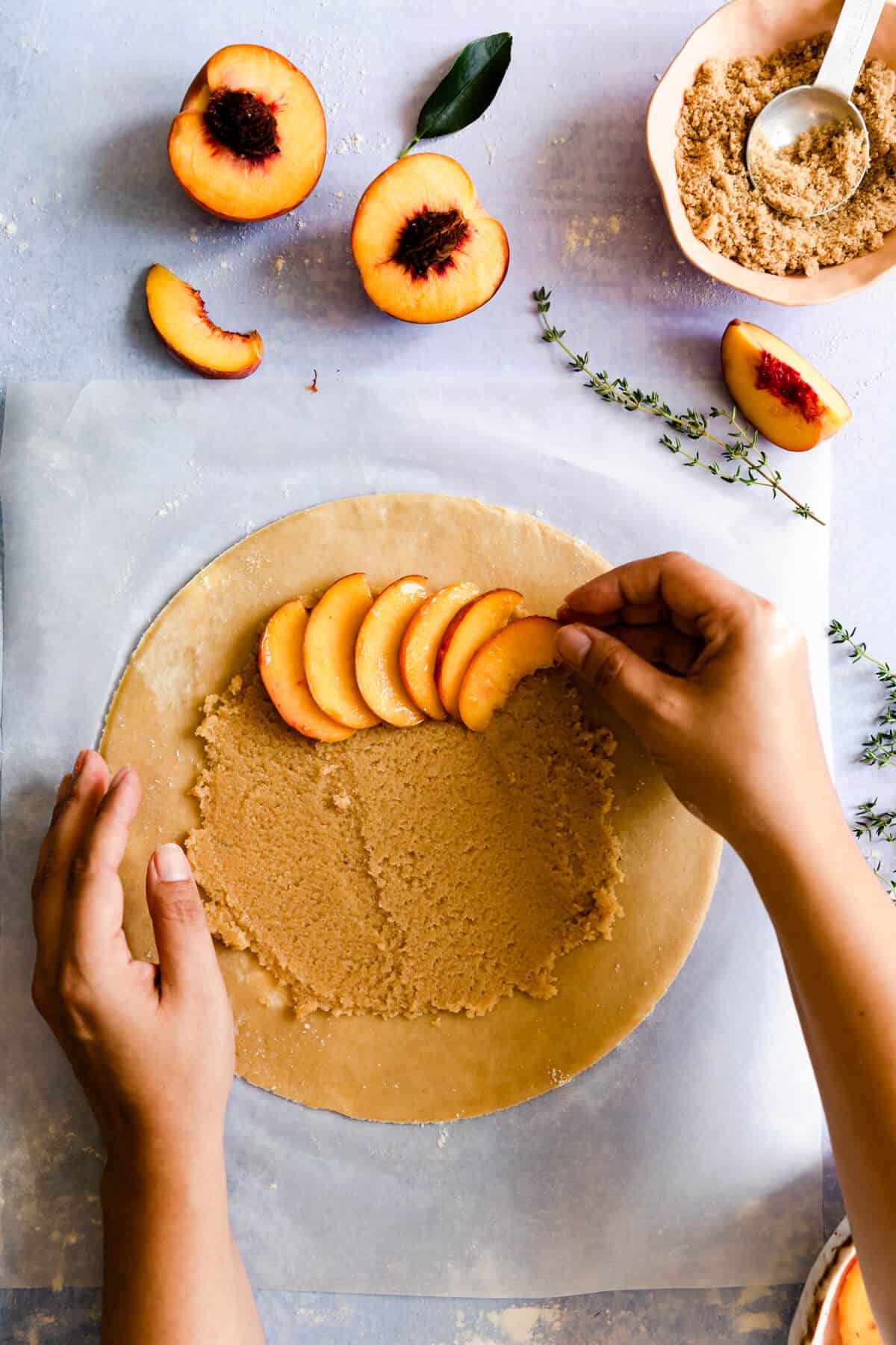 top view of sliced peaches being arranged onto galette dough