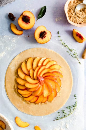 top view of large circle of dough topped with sliced peaches
