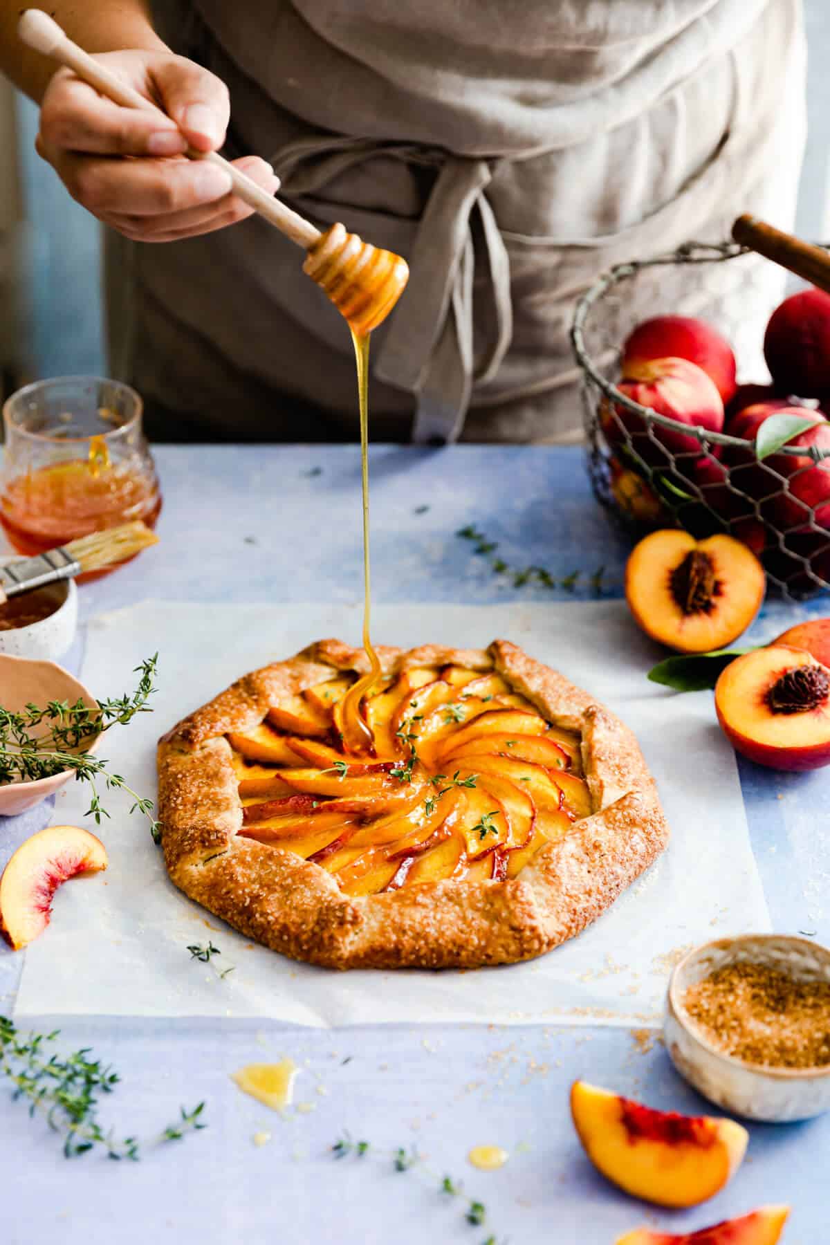 side angle showing a person drizzling honey on peach galette