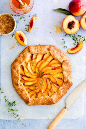 top view of baked peach galette with fresh thyme sprinkled on top