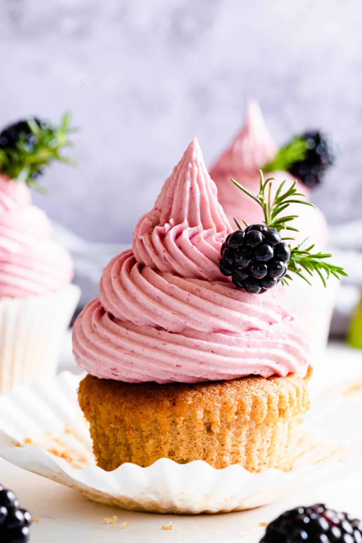 super close up of a cupcake with blackberry buttercream in a paper case