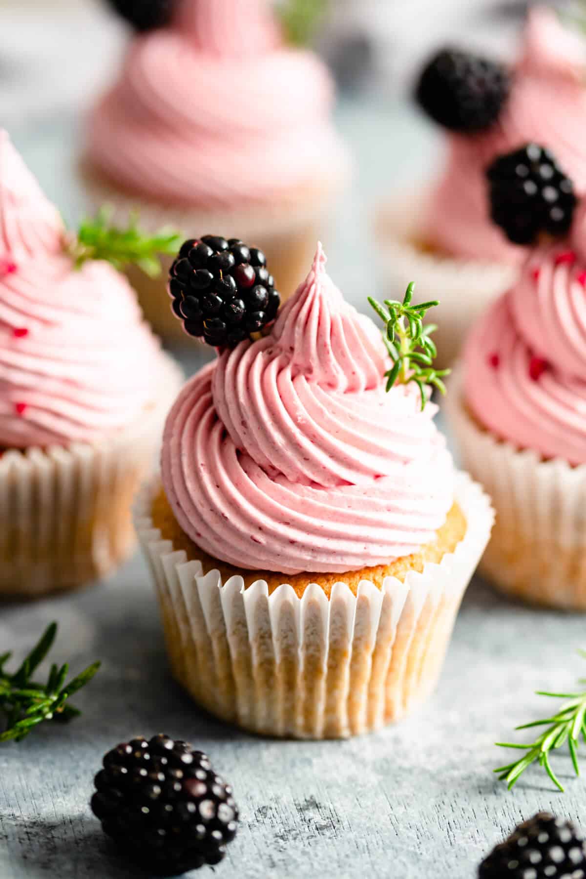 super close up of a cupcake topped with pink buttercream and fresh blackberry