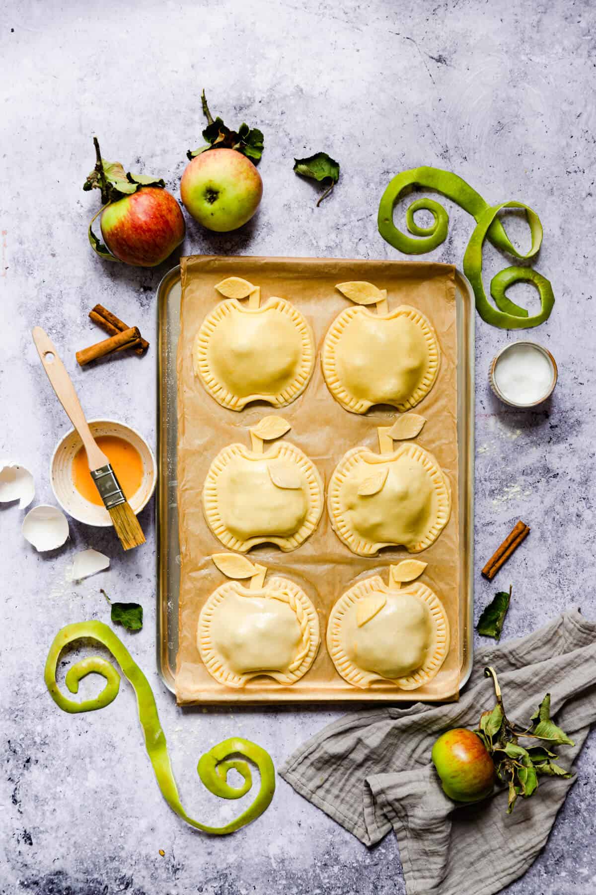 overhead shot of hand pies shaped into apples on a baking tray