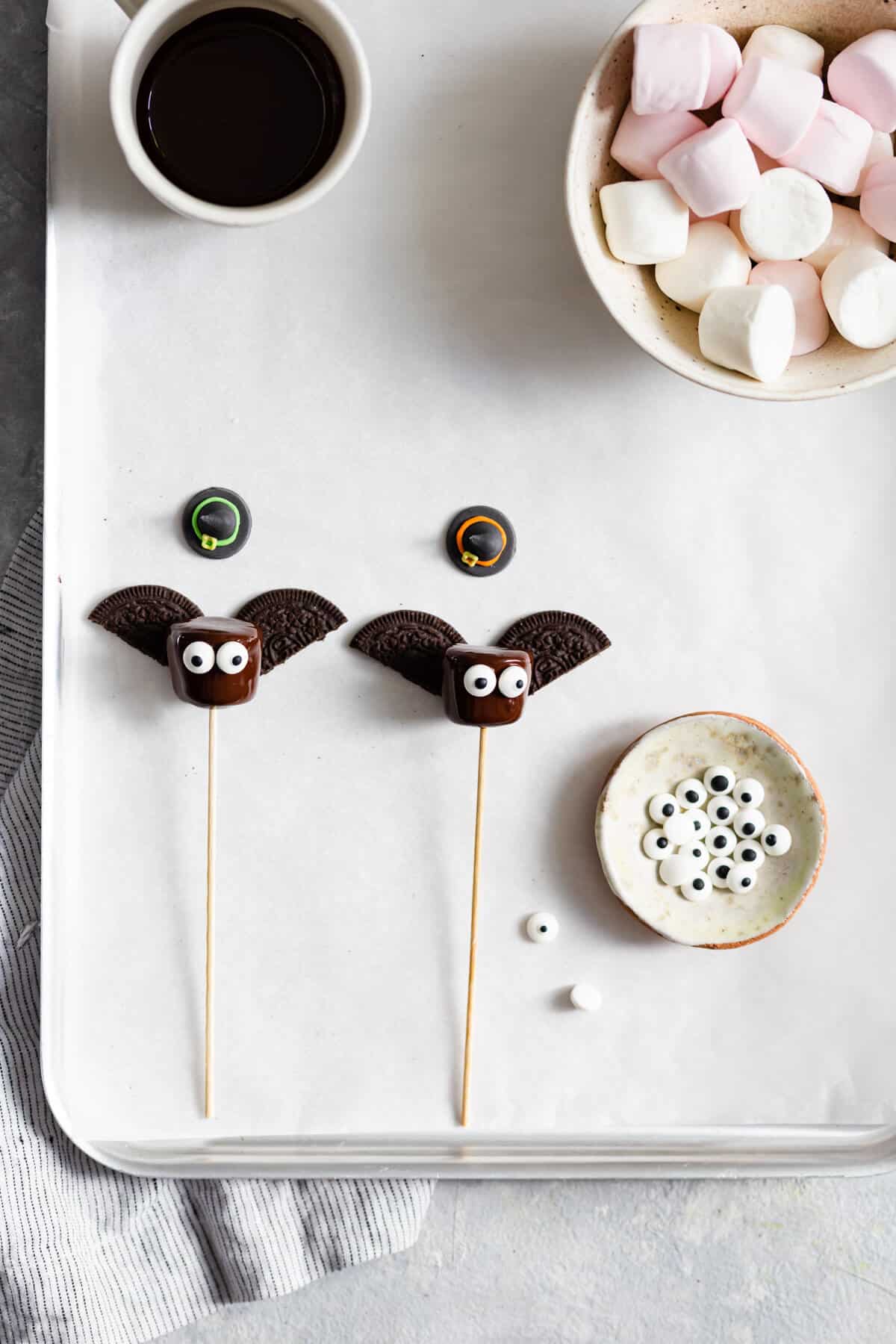overhead shot of chocolate dipped marshmallows with cookie wings and sugar eyes attached to them