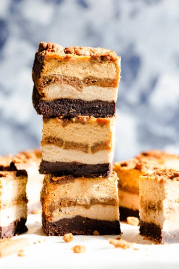 side angle shot of three slices of pumpkin biscoff cheesecake brownies stacked on top of each other