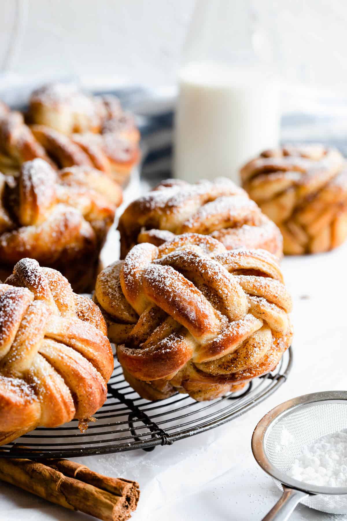 side shot of cinnamon buns shaped into knots and dusted with icing sugar