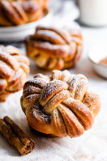 side close up of cinnamon bun twisted into a knot with icing sugar on top