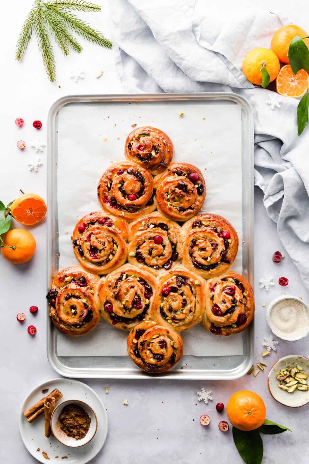 top view of orange and cranberry Chelsea buns shaped into festive tree on a baking tray