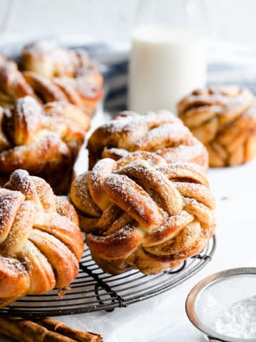side shot of cinnamon buns shaped into knots and dusted with icing sugar