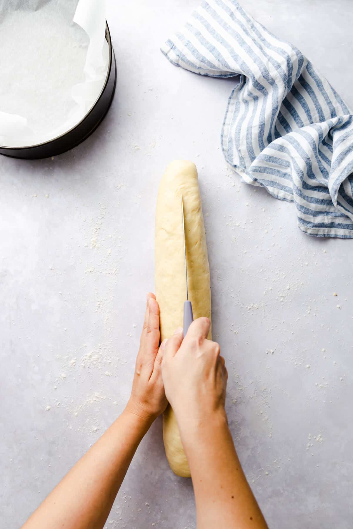 top view of a person slicing a log of dough in half