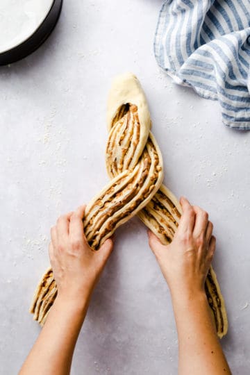 overhead shot of a person shaping twisted cinnamon and hazelnut bread