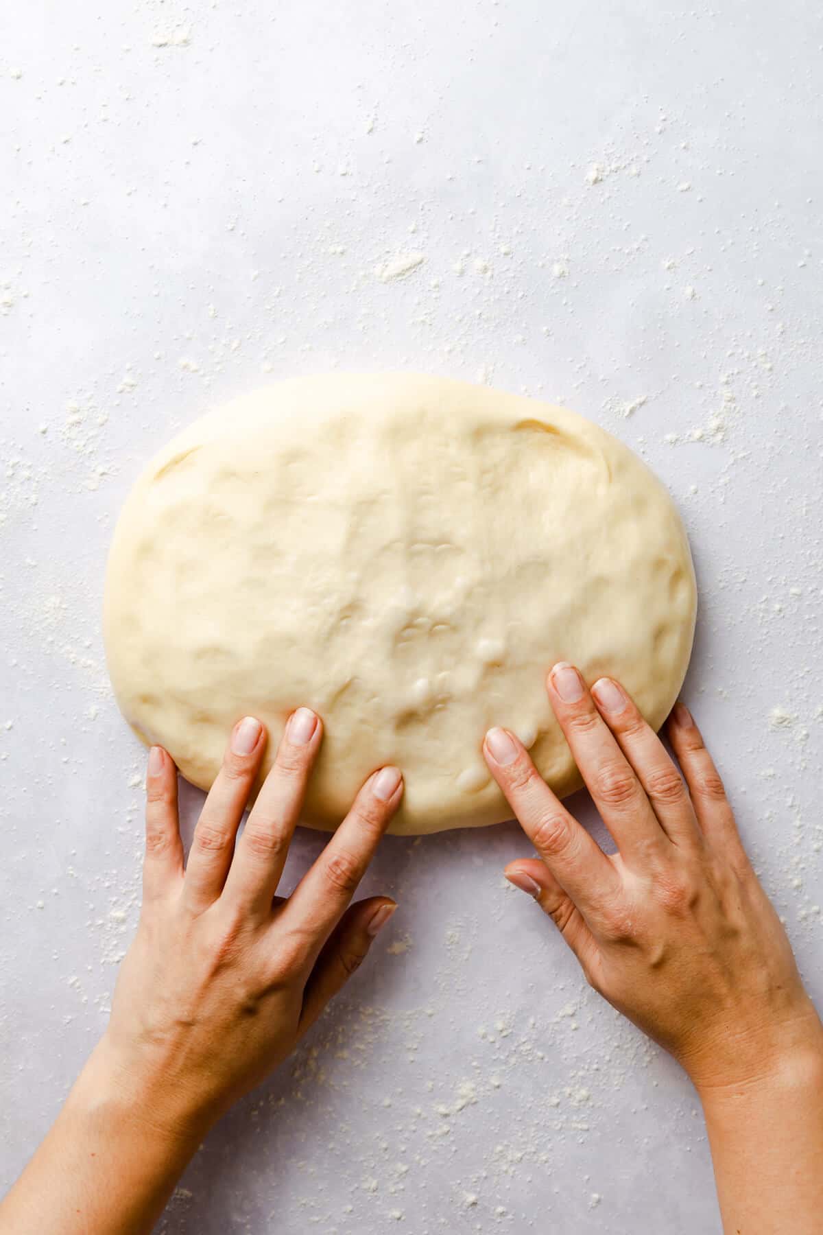 top view of person knocking the air out of soft dough