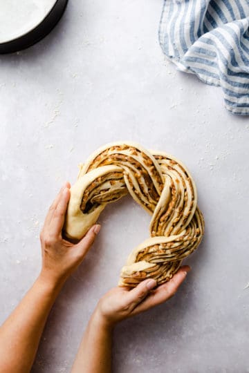 overhead shot of a person shaping twisted cinnamon bread into a circle