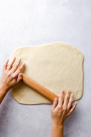 top view of a person rolling the dough into rectangle with rolling pin