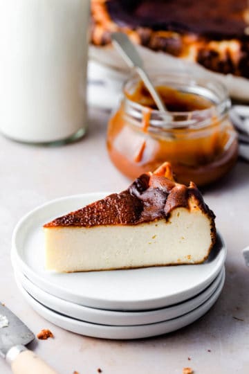 slice of a burnt Basque cheesecake with caramel jar behind it.