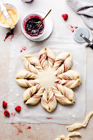 overhead shot of a dough shaped into a star bread filled with raspberry jam