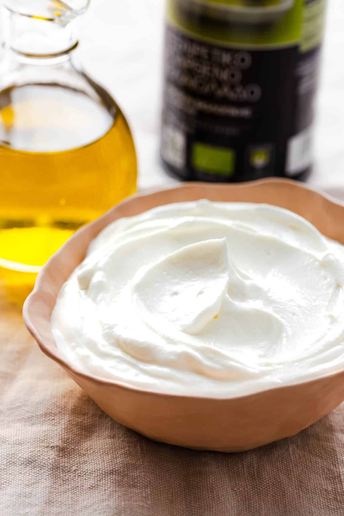 side close up of a bowl with Greek yogurt and some olive oil in the background