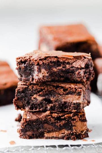 side close up at a stack of three brownies with the top one missing a bite