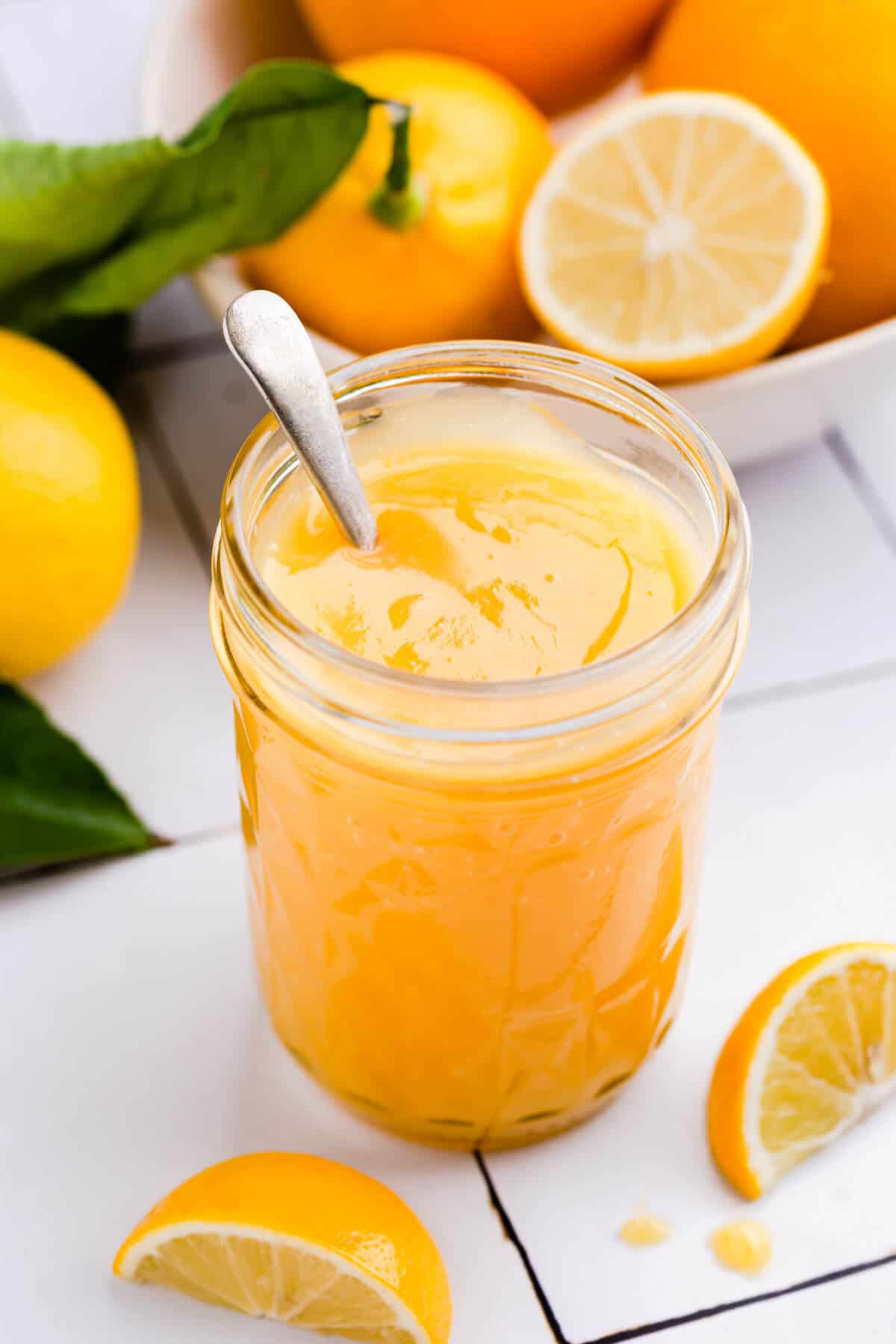 45 degree angle shot of a jar with citrus curd and small spoon inside of the jar