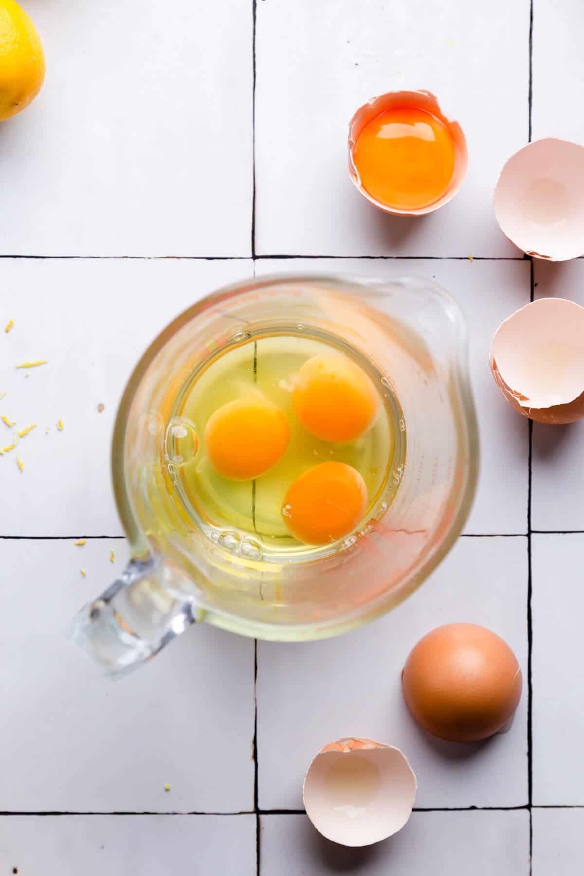 overhead shot of a glass jar filled with 3 eggs and an egg yolk on side