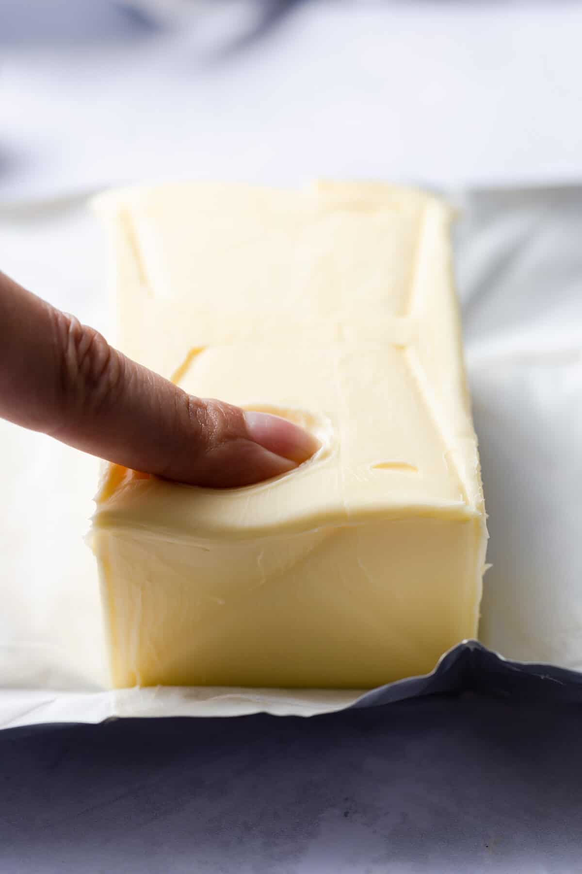 side angle of an index finger making indent in a block of butter