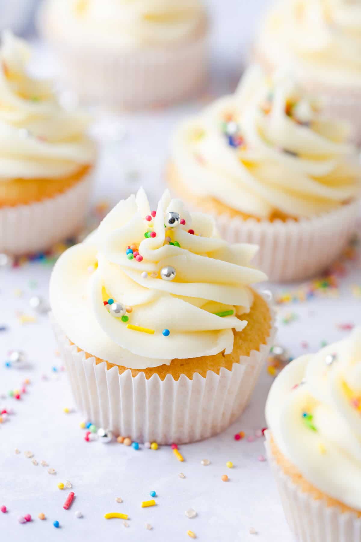 45 degree angle photo of one bowl vanilla cupcake topped with sprinkles and buttercream
